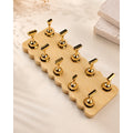 Nail tip display stand with ten gold-tone holders in two rows on a rectangular wooden base with scalloped edges.