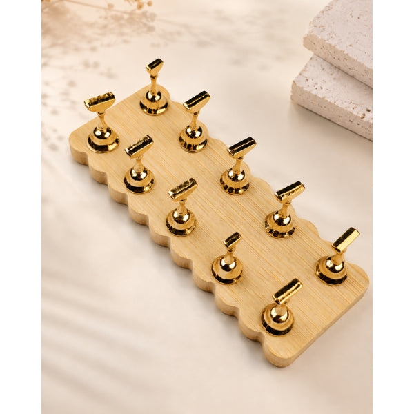 Nail tip display stand with ten gold-tone holders in two rows on a rectangular wooden base with scalloped edges.