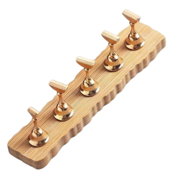 Nail tip display stand with five gold-tone pedestal holders arranged in a row on a wooden base with scalloped edges.